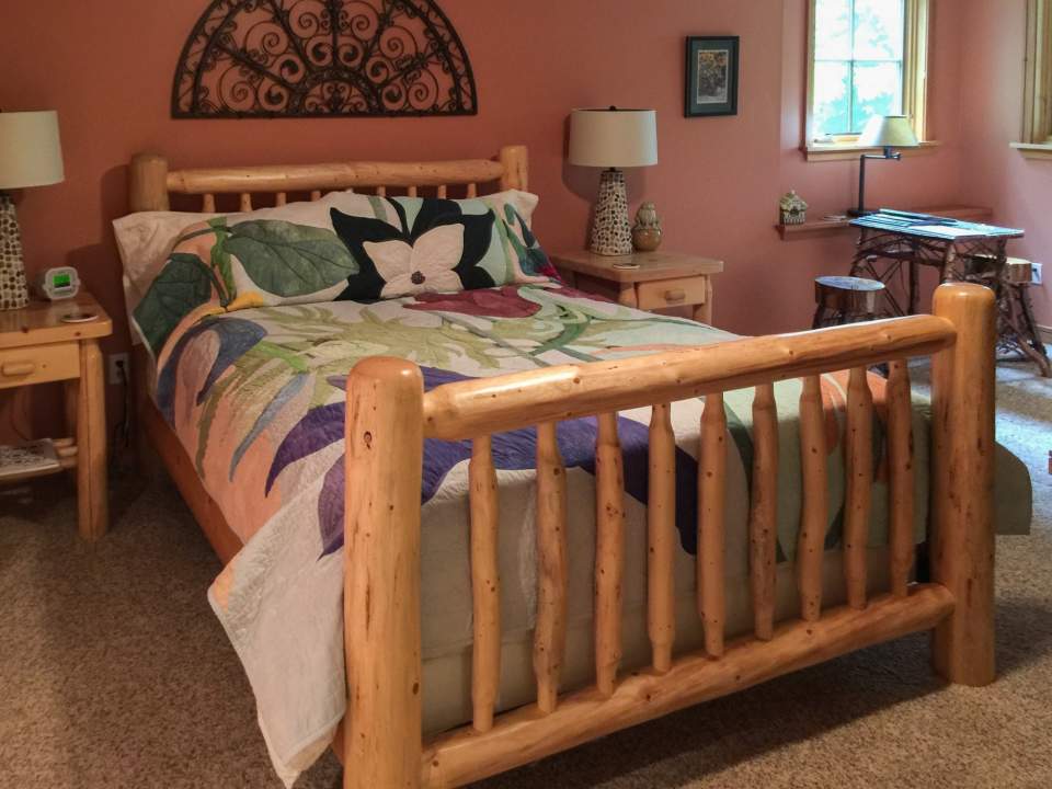 Inside a guest room showing a comfortable bed with a wooden bed frame.