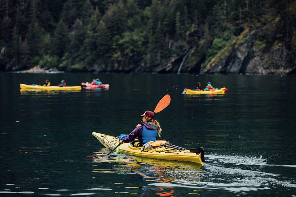 3 sea kayakers paddle near Fox Island in Resurrection Bay, Alaska