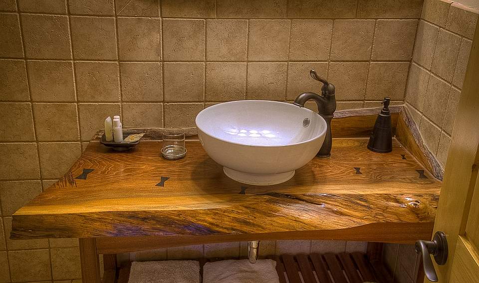 A bathroom sink with a wooden counter top.