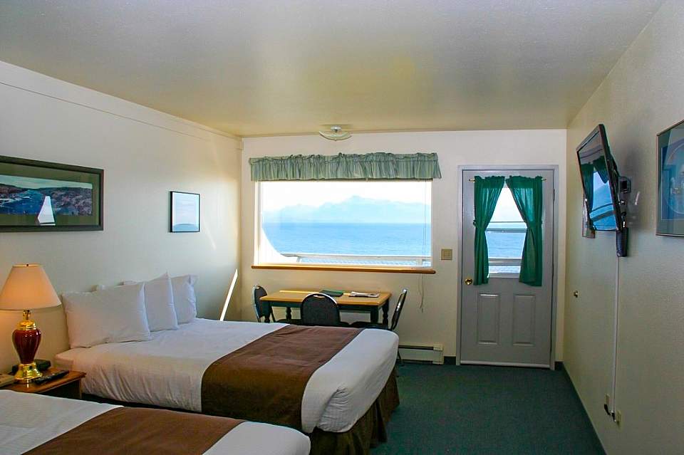 Inside of a guest room at the Ocean Shores Hotel with views from the window looking out onto the ocean.