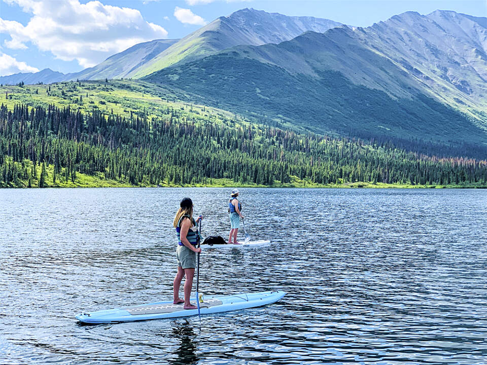 Guest at Rainy Pass Lodge paddleboards on the lake