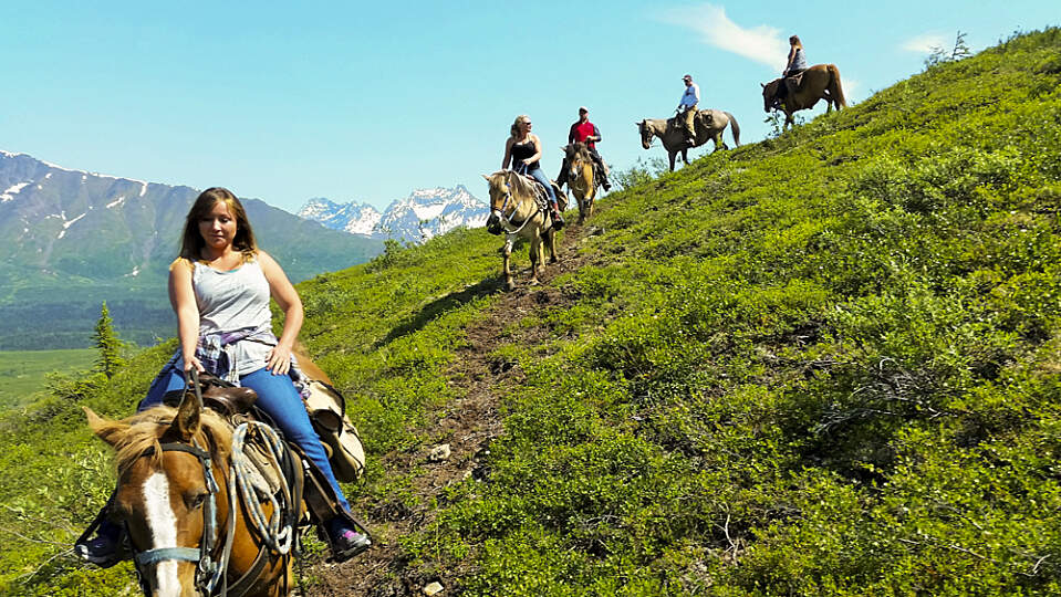 Group rides horses through the Alaska mountains