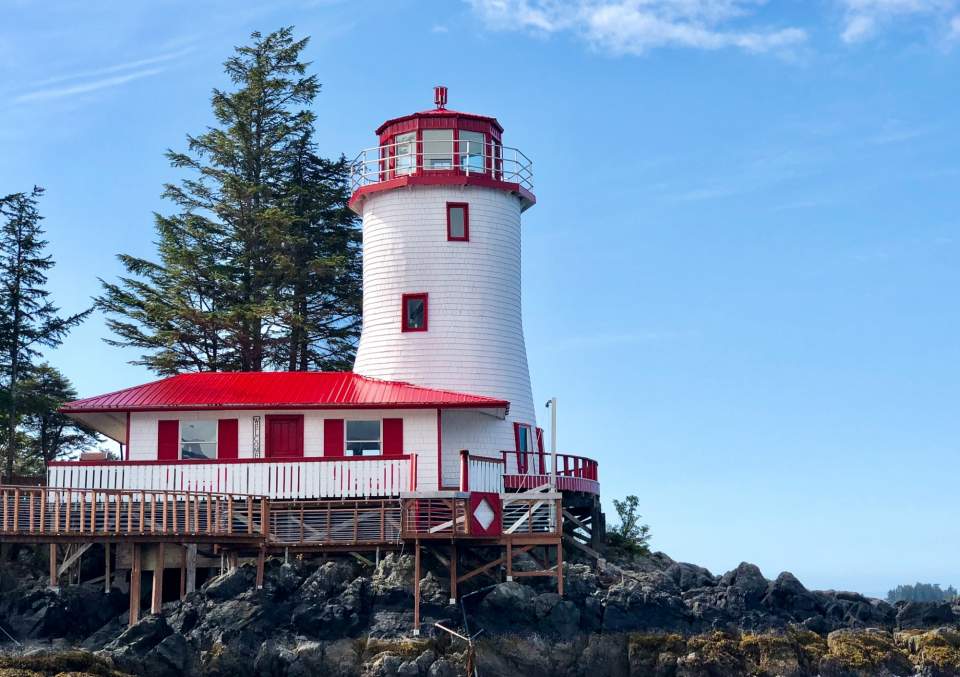 A red and white lighthouse with blue skies in the background.