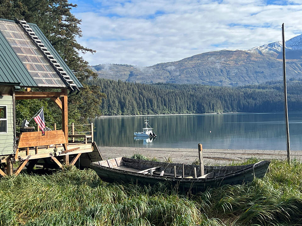 Beach house with sunrise, water, and mountains in the background