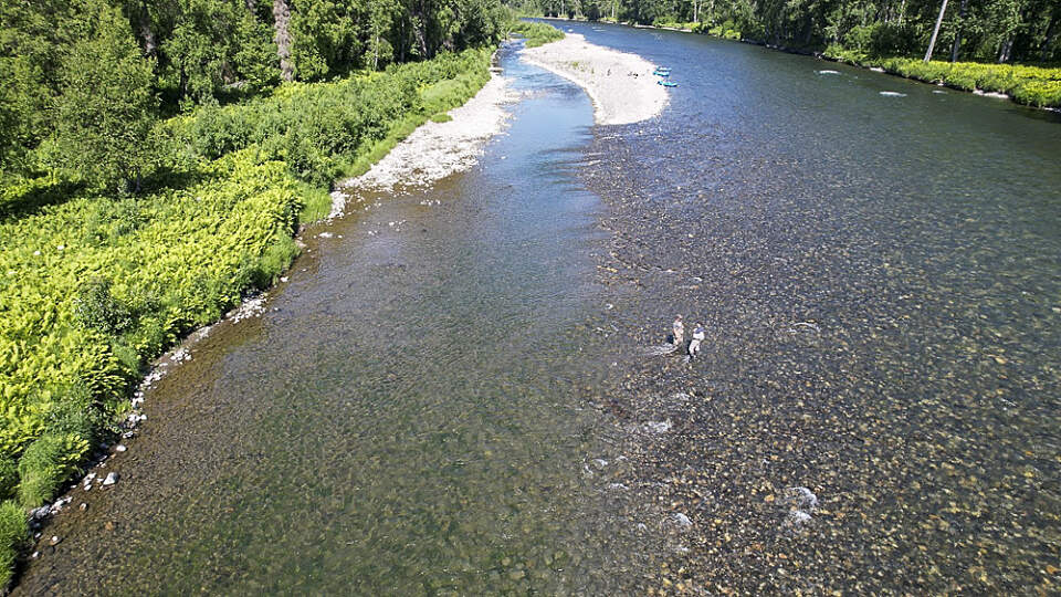 two fishermen stand in a river by wilderness place lodge in Alaska