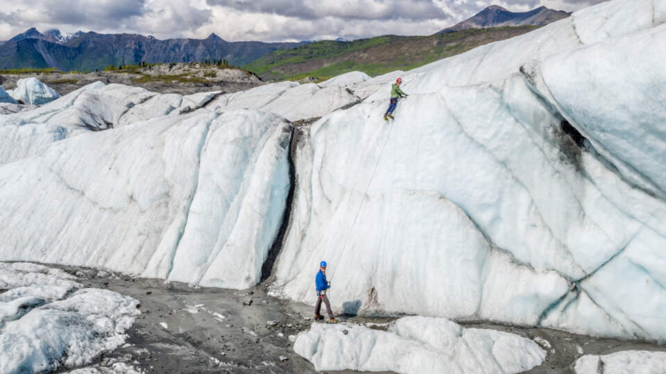 Boy scales the Matanuska Glacier with the help of a guide