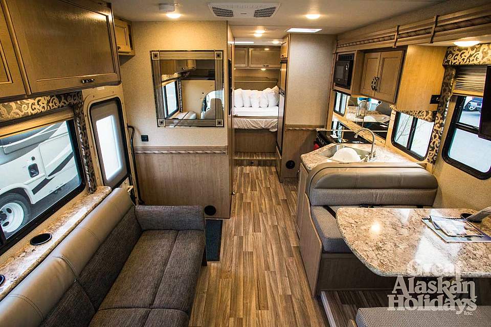 Inside of an RV showing the living area, kitchen, and sleeping area.